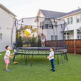Bild in Galerie-Viewer laden, A young girl playing on a trampoline, and her brothers playing a ball outside