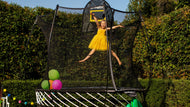 Charger l'image dans la visionneuse de galerie, A gril in yellow dress playing on a trampoline with balloons in it