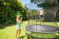 Charger l'image dans la visionneuse de galerie, A girl playing on a trampoline, a woman standing beside it