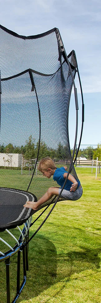 a kid leaning on a net of a trampoline